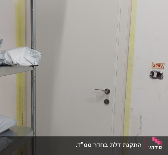 דלת לבנה עם ידית מתכת ושלט יציאה מעליה